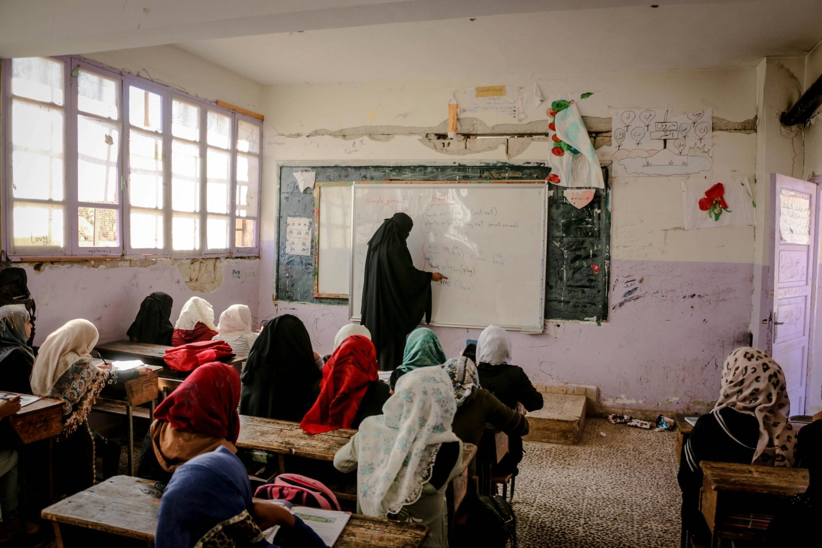 A teacher in Syria leads a classroom lesson for young students wearing hijabs.