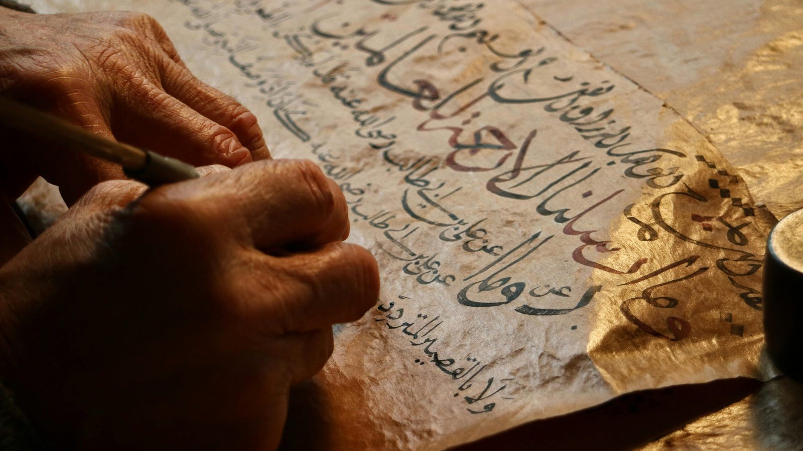 Close-up of artisan creating calligraphy on aged paper, showcasing traditional craftsmanship.